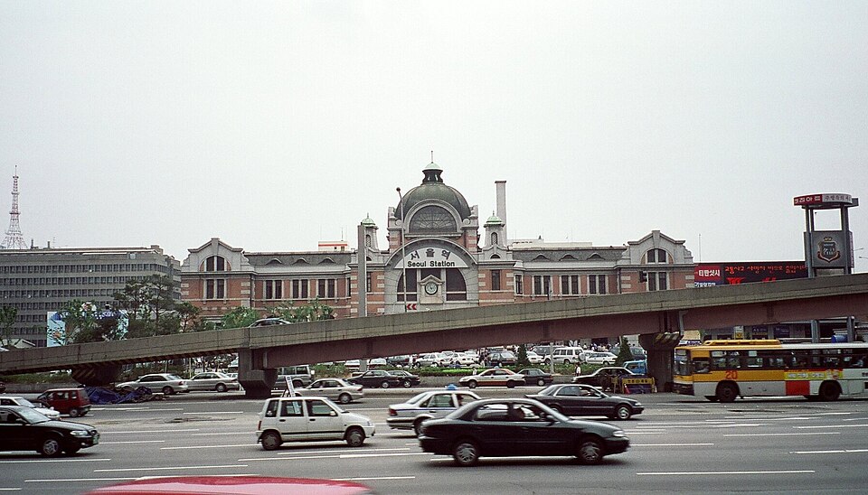도로 건너에서 본 구 서울역. 붉은 벽돌 외벽 앞에 고가 구조물과 차량이 보입니다.